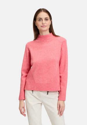 Pull en laine rose avec un col montant et des poignets côtelés, doté d'une poche avant. Fabriqué en tissu tricoté texturé, il a une coupe décontractée.