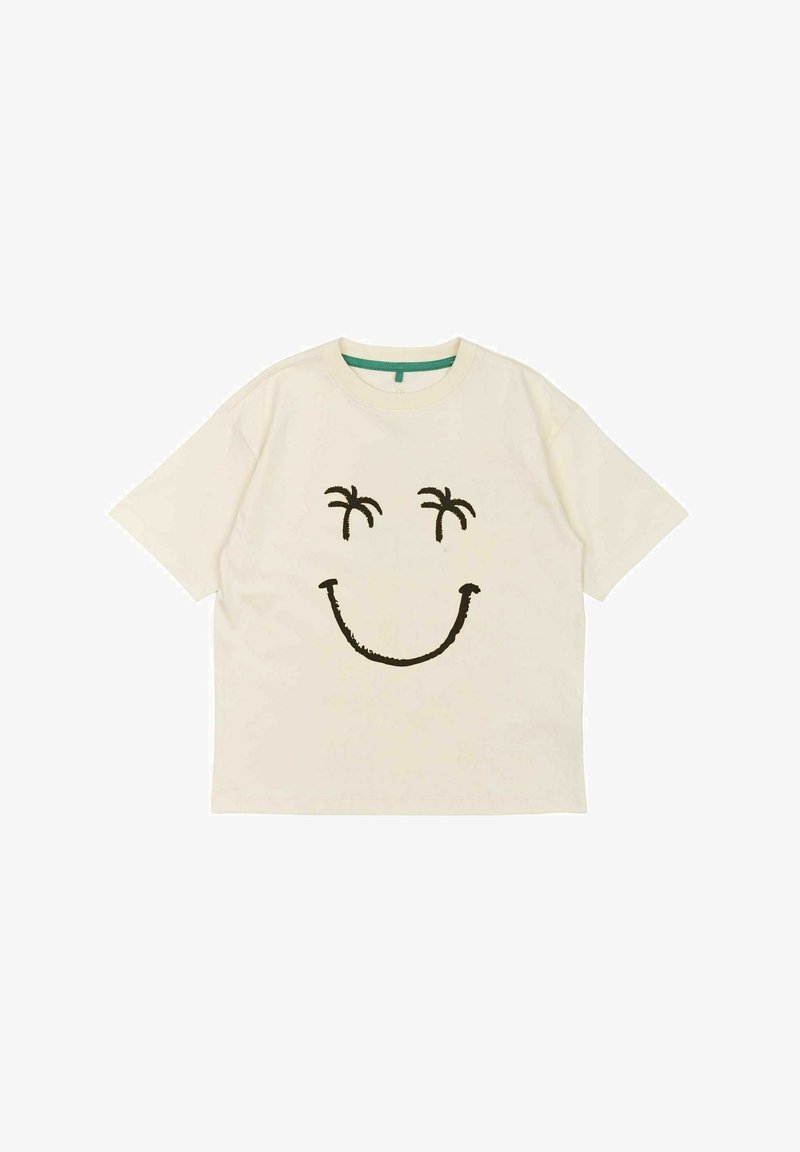 Camiseta de algodón color crema con un diseño de cara sonriente negra que presenta palmeras como ojos. Tiene mangas cortas y un cuello redondo.