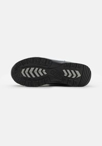 Suela de zapato negra con un patrón texturizado, que presenta un diseño de agarre en zigzag y acentos grises. El material parece ser de goma para mayor tracción.