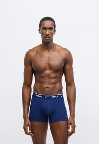 Pánske boxerky tmavomodrej farby s bielym pásom s logom Nike. Vyrobené z hladkej látky, s priliehavým strihom a nohavičkami s dĺžkou po polovicu stehna.
