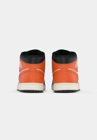 Hochschnittige Sneaker aus lebhaftem orangefarbenem Leder mit schwarzen Akzenten. Sie verfügen über einen gepolsterten Kragen, eine weiße Mittelsohle und eine strukturierten schwarzen Außensohle.