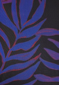Feuilles tropicales bleues et violettes avec des accents rouges sur un fond en tissu noir texturé.