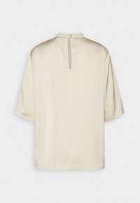 Lys beige satinvare kortærmet top med rund halsudskæring, der har et nøglehul bagpå, som lukkes med en knap. Glat tekstur.