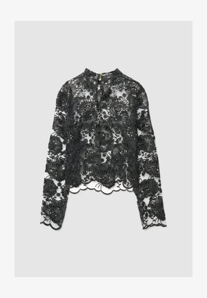 Blouse noire à manches longues en dentelle avec broderie florale, présentant un ourlet festonné et un col montant avec une fermeture en trou de serrure.