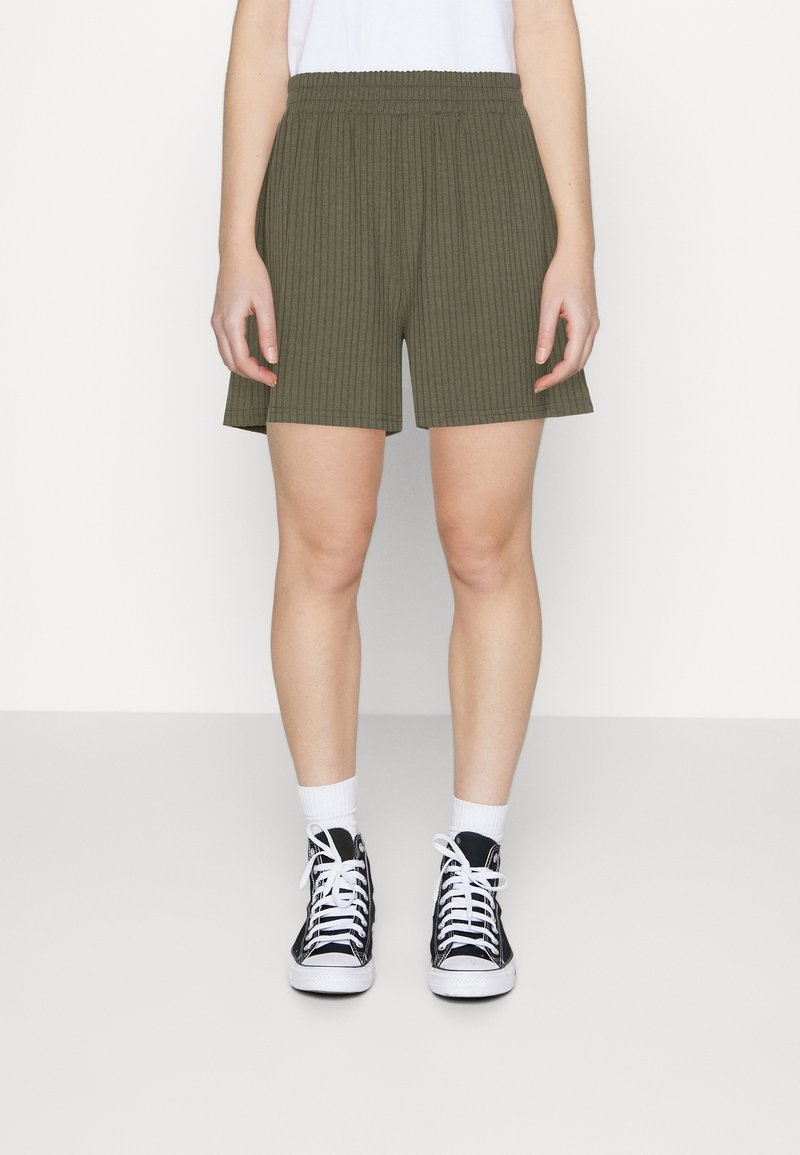 Shorts côtelés vert olive avec une taille élastique, coupe droite et poches latérales, associés à des baskets montantes noires et des chaussettes blanches.