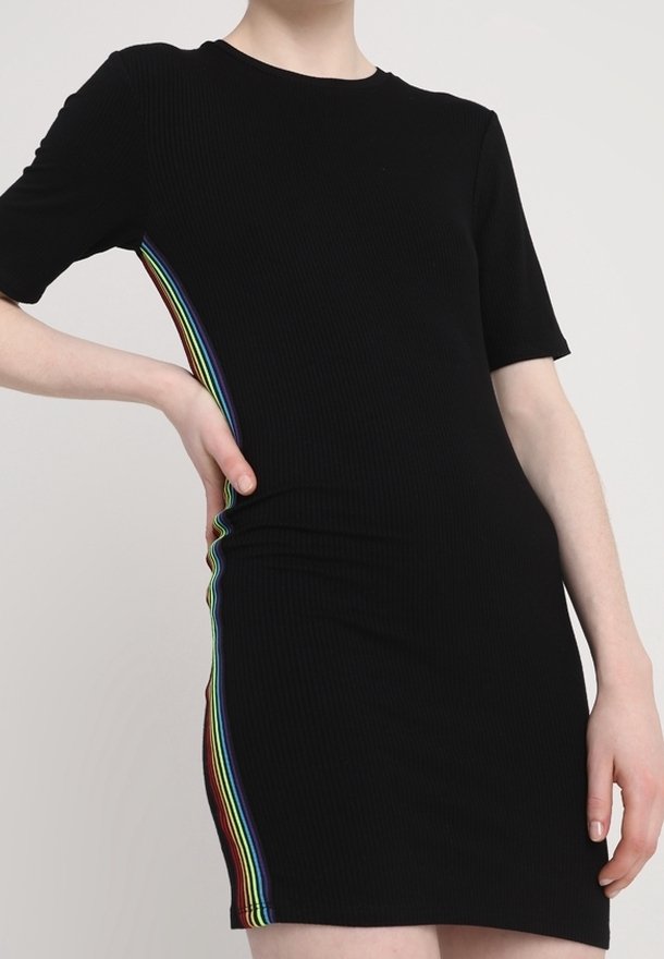 Svart ribbad klänning med kort ärm som har en regnbågsrandig sido panel. Klänningen har en figurnära silhuett och en klassisk rund halsringning.