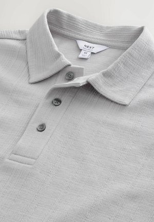 Hellgraues Poloshirt aus strukturiertem Stoff, mit einem kragen, drei Knöpfen und einem schlichten Design mit dezenten Mustern.