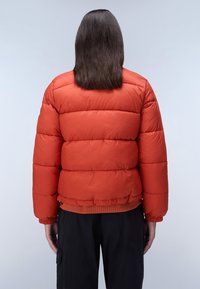 Rode pufferjas met een gequilt design, elastische manchetten en een getailleerde taille. De stof lijkt glanzend en glad, met een losse pasvorm.