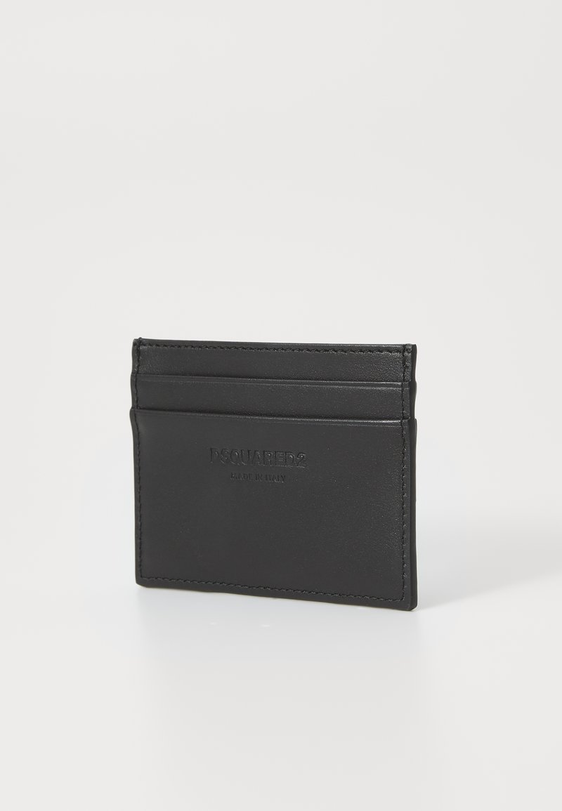 Cartão preto em couro com quatro slots para cartões e logo em relevo. Textura suave com costura mínima nas bordas. Design compacto.