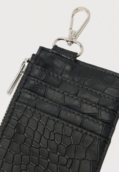 Μαύρο πορτοφόλι από δερμάτινη υφή με σχέδιο κροκόδειλου, που διαθέτει πολλές θήκες για κάρτες, ένα φερμουάρ και ασημένιο κλιπ.