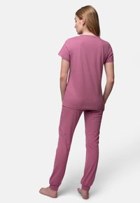 Set di pigiama in cotone rosa composto da una maglietta a maniche corte e pantaloni a tapered con polsini elasticizzati, visto da dietro.