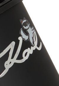 Czarna puszka posiada srebrny grafikę kota oraz imię "Karl" w kursywie, podkreślając zabawne elementy projektu.