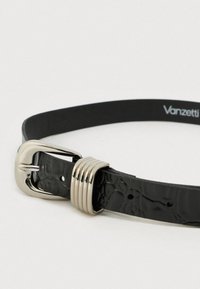 Mustast nahast vöö, millel on tekstuuriga pind, suur hõbedane pandlaga ja kolm dekoratiivset metallrõngast ning mitu suuruse käeava.