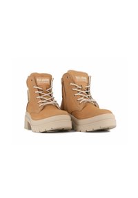 Stivali alla caviglia in pelle tan con lacci beige, colletto imbottito e suole in gomma. Presentano una cerniera laterale e un logo sulla linguetta.