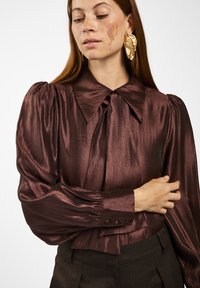 Bordeaux satijnen blouse met een grote kraag,Gathered mouwen en knoopmanchetten. De stof heeft een gladde, glanzende textuur, wat een vloeiende uitstraling creëert.