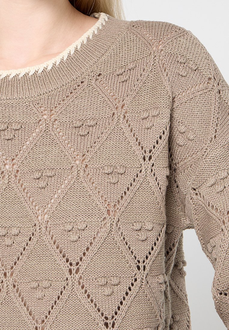 Maglione lavorato a maglia beige con una texture a diamante, dettagli in pizzo e un colletto di colore crema in contrasto.