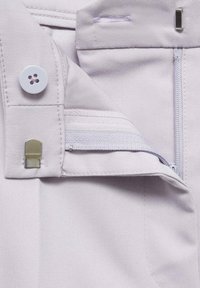 Tânăr purpuriu deschis din țesătură cu un buton, fermoar și clasp metalic. Dispune de margini cusute și o textură netedă. Detaliul buzunarului cu fermoar este vizibil.