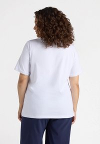 Camiseta blanca de manga corta hecha de un tejido suave con un corte relajado, que presenta un cuello redondo y un diseño minimalista.