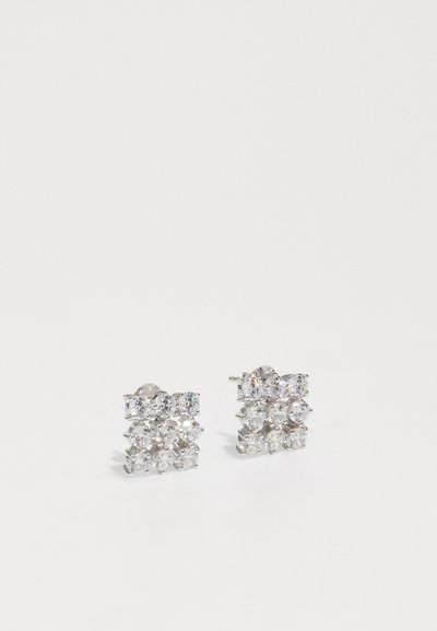 Λαμπερά σκουλαρίκια με στυλ στήριξης που διαθέτουν μια σύνθεση από διάφορες στρογγυλές και μαρκίζ κομμένες διάφανες πέτρες σε μεταλλική απόχρωση ασημιού.