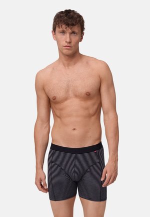 Svart och vit randiga boxerkalsonger med ett svart elastiskt midjeband med text. Slät textur, figurnära design och kort benlängd.