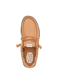 Zapato de tela beige tipo slip-on con puntera redonda, suela texturizada en contraste, acento de cordones y forro interior con estampado. Logo visible en la plantilla.