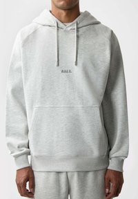 Harmaa huppari, joka on valmistettu pehmeästä materiaalista, sisältää kengurupussin ja resorit hihansuissa. Rinnassa on brodeerattu "BALR." -logo.