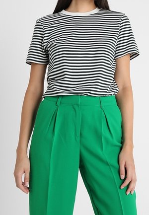 Černobíle pruhované tričko s krátkými rukávy v kombinaci s vysokým pasem, plisovanými zelenými kalhotami z lehké látky.