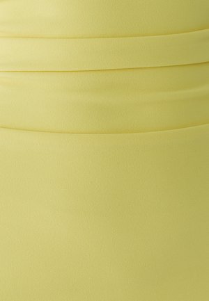 Close-up van zacht geel stof met horizontale plooien en een licht gestructureerd oppervlak.