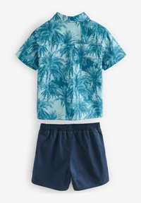 Korte mouwen shirt in blauw met palmboomprint, gecombineerd met marineblauwe shorts met een elastische tailleband. Katoenmix materiaal.