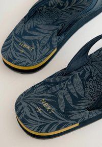 Infradito blu navy con un motivo botanico testurizzato, caratterizzati da un accento giallo sulla suola e il marchio inciso "NEXT" sulla soletta.