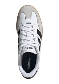 Baskets blanches et grises avec tige en daim et cuir, bandes noires et semelle extérieure en caoutchouc. Dotées de lacets blancs et d'une languette avec logo.