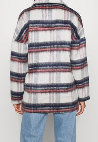 Fleece jack met een geruit patroon in grijs, marineblauw en roze. Kenmerkt zich door een relaxte pasvorm en lange mouwen, met een zachte textuur.