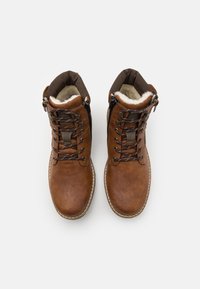 Botas de cuero marrón hasta el tobillo con un acabado texturizado, cordones marrones, cremalleras laterales y un forro suave de color crema.