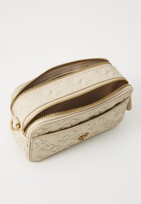 Beige geperforeerde leren cosmetica tas met twee gouden ritsen, een gestructureerde vorm en een gladde binnenvoering. Voorzien van logo-detail aan de voorkant.