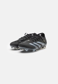 Zwarte voetbalschoenen met drie lichtblauwe strepen, van gestructureerd synthetisch materiaal, met vetersluiting en gevormde noppen voor grip.