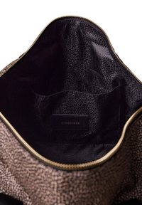 Interno della borsa in tessuto marrone scuro con una finitura morbida e lucida. Presenta un'etichetta in pelle con il marchio e una piccola tasca laterale. Dettaglio della cerniera dorata.