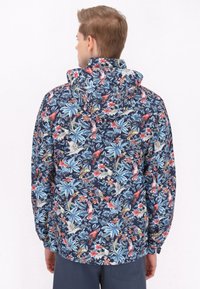 Giacca a cappuccio blu navy con motivi floreali e di uccelli in colori vivaci. Presenta polsini elastici e un design a vestibilità rilassata.