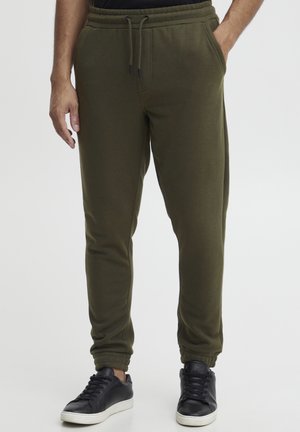 Olivgröna sweatpants tillverkade av mjukt material, med resårmidja och dragsko, sidofickor och smalnande avslut.