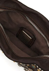 Interno di borsa in pelle marrone con una texture liscia, chiusura con cerniera e fodera in tessuto. Include una targhetta metallica con il marchio e dettagli decorativi.