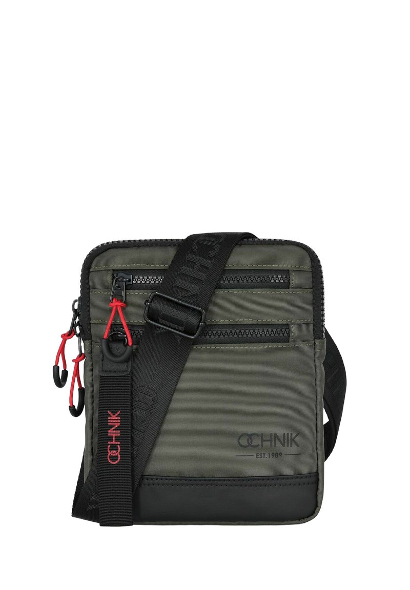 Ciemnozielona nylonowa torba na ramię z dwiema zasuwanymi przegródkami, czarnymi akcentami, czerwonymi suwakami oraz czarnym regulowanym paskiem. Logo nadrukowane na czerwono.