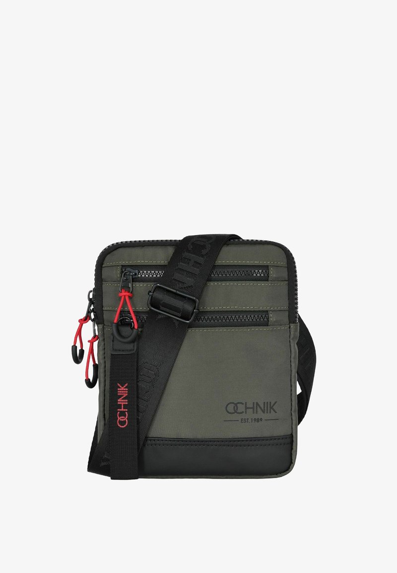 Ciemnozielona nylonowa torba na ramię z dwiema zasuwanymi przegródkami, czarnymi akcentami, czerwonymi suwakami oraz czarnym regulowanym paskiem. Logo nadrukowane na czerwono.