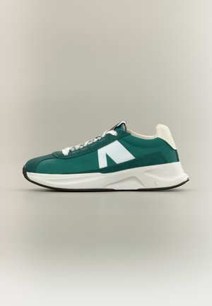 Green sneaker with a white logo, featuring a smooth upper material and textured accents. Thick white sole with black outsole.