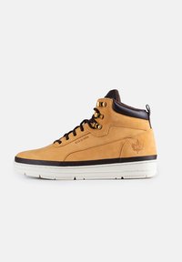 Sneaker mid-top in pelle tan con accenti marroni, occhielli dorati, suola bianca e logo impresso. Presenta una finitura liscia e un collare testurizzato.