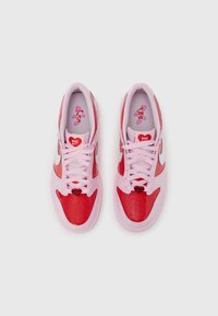 Κόκκινα και ροζ παπούτσια Nike με λείο δερμάτινο επάνω μέρος, διακοσμητικά τρύπες, κλειδαριά κορδονιών σε σχήμα καρδιάς και γραφικά εσωτερικά πέλματα.