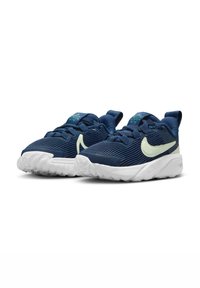 Zapatillas deportivas navy con parte superior de tela texturizada, suela de goma blanca y detalle del swoosh de Nike en verde claro. Cuenta con diseño de cordones y tiras en el talón.