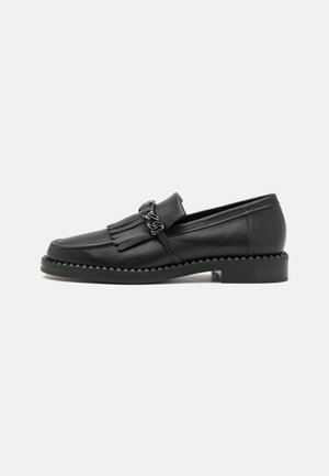 Mocassins en cuir noir avec des accents en franges, un bout arrondi et une semelle chunky avec des bords dentelés. Détail décoratif en chaîne à l'avant.
