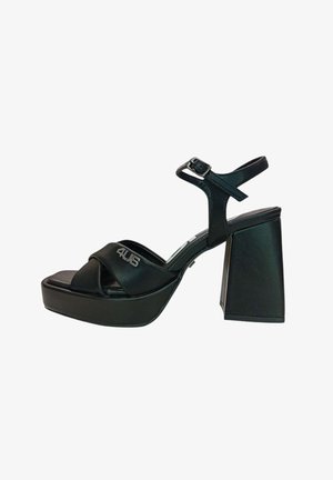 Sandalo platform in pelle nera con tacco largo a blocco, fibbia alla caviglia e cinturini frontali incrociati con piccolo logo in metallo.