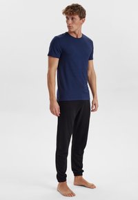 Navy crew-neck t-shirt with short sleeves, paired with black tapered joggers. Fabric appears soft with elastic cuffs at the pant hems.