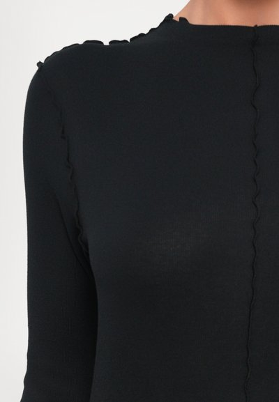 Black ribbed long-sleeve top featuring a scalloped neckline and seam detailing along the shoulder, with a fitted silhouette.