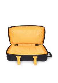 Musta matkalaukku, jossa on oranssi sisustus. Ominaisuuksiin kuuluu tilava osasto, keltaiset hihnat ja vetokahva.